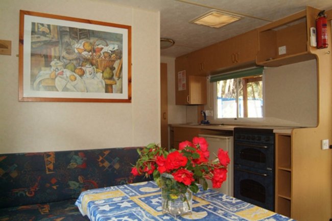 Cucina con tavolo apparecchiato e rose rosse, dipinto di natura morta appeso.