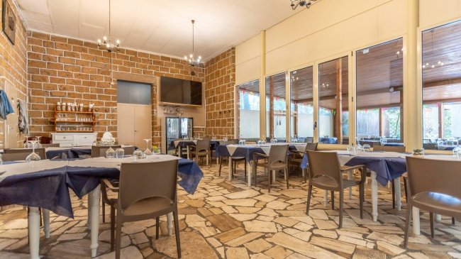 Sala da pranzo con tavoli blu e pareti in pietra.