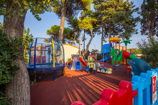 Un parco giochi colorato con altalena, scivoli e giochi per bambini tra gli alberi.
