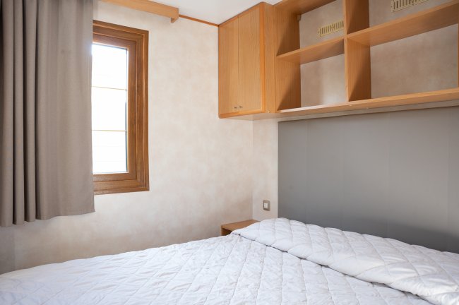 Camera con letto matrimoniale, finestra, armadio a muro e mensole.