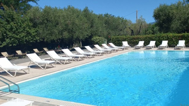 Piscina all'aperto con lettini bianchi.