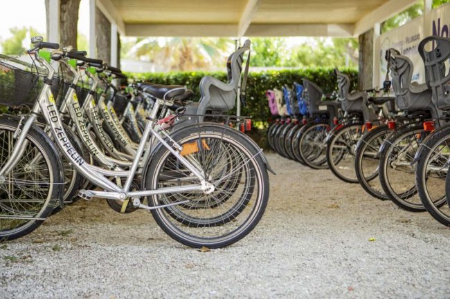 Fila di biciclette con seggiolini per bambini in un'area coperta.