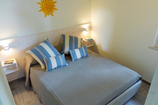 Camera da letto con cuscini a righe blu e decorazione a forma di sole.