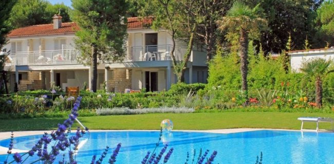 Piscina con giardino e casa sullo sfondo.