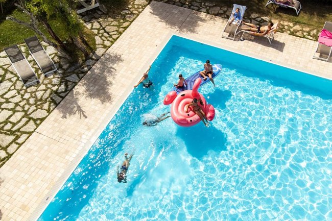 Persone su gonfiabile rosa in piscina.