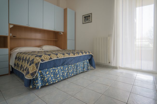 Camera con letto matrimoniale, copriletto a motivi geometrici.