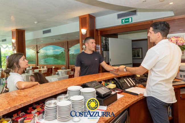 Due persone in reception si stringono la mano in un hotel.