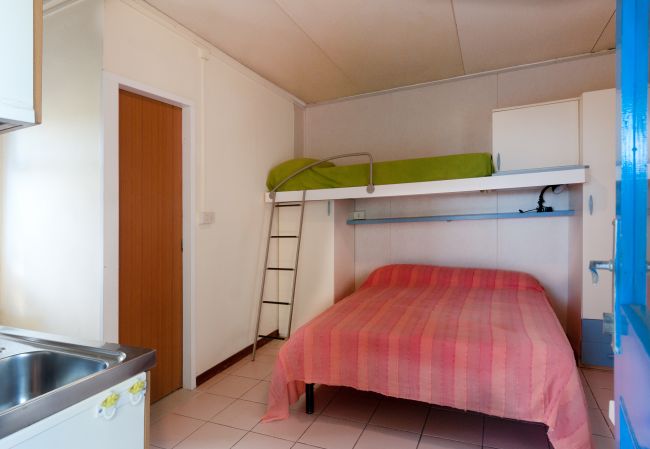 Camera con letto matrimoniale, letto a soppalco verde e piccolo lavello.