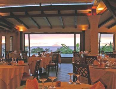 Ristorante con vista panoramica, tavoli apparecchiati e tramonto.