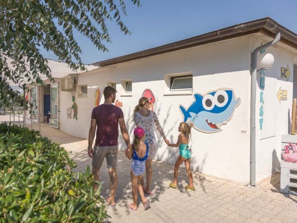 Famiglia cammina verso una struttura decorata con disegni di pesci.