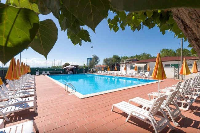Piscina all'aperto con sdraio e ombrelloni gialli.