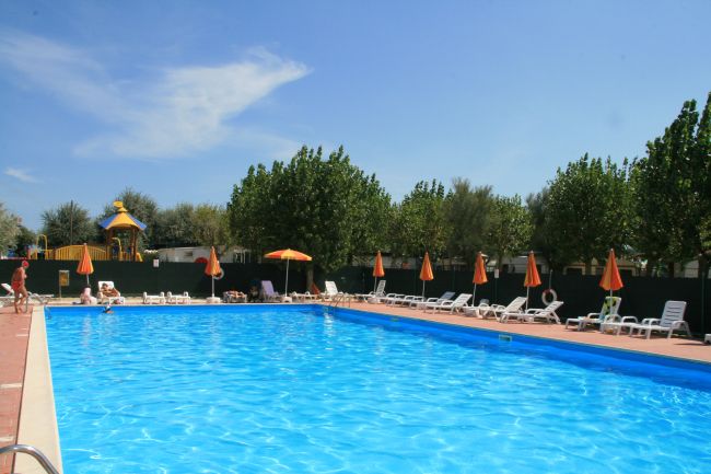 Grande piscina all'aperto con lettini e ombrelloni arancioni.