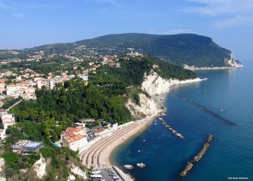 Veduta aerea di una costa con spiagge, scogli e città collinare.