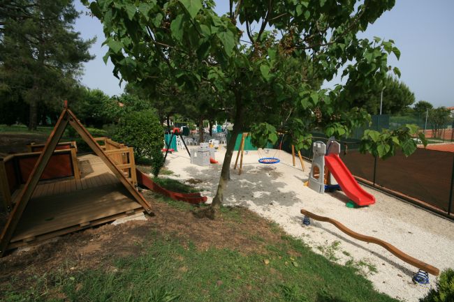 Un parco giochi con scivoli e aree gioco tra gli alberi.