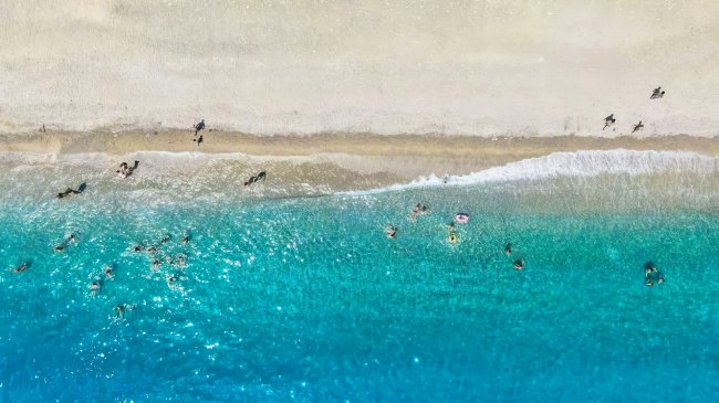 Vista aerea di una spiaggia con persone in acqua.