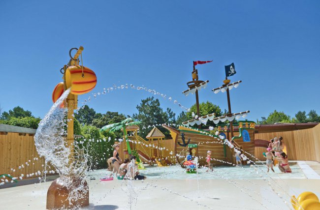 Un parco acquatico con giochi a tema pirata e bambini che giocano sotto gli spruzzi d'acqua.