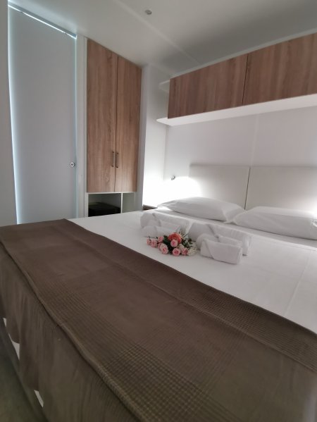 Letto matrimoniale con coperte marroni, decorato con fiori e asciugamani.