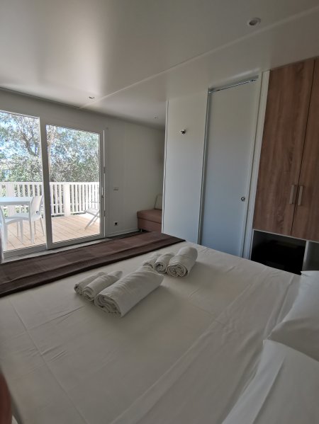 Camera luminosa con letto matrimoniale, asciugamani e balcone vista giardino.