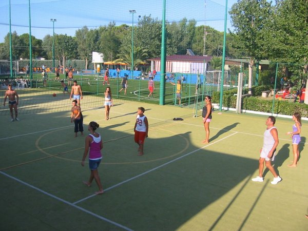 Partita di pallavolo su un campo all'aperto con persone impegnate a giocare.