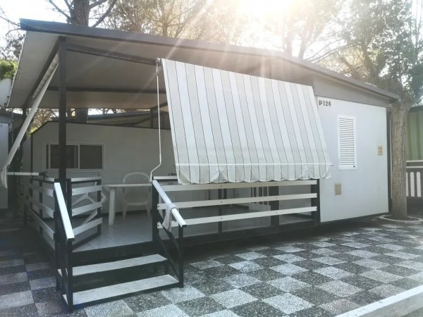 Veranda coperta di una struttura con tenda a righe e sedie di plastica.