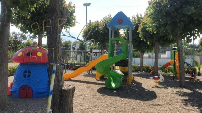 Parco giochi con scivoli colorati e casetta a fungo.