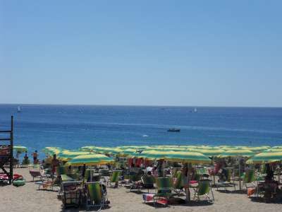 Spiaggia con ombrelloni gialli e verdi e molte persone.