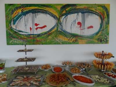 Buffet con piatti vari e un quadro astratto colorato sullo sfondo.