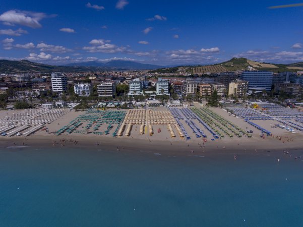 Spiaggia affollata con ombrelloni colorati e mare calmo.