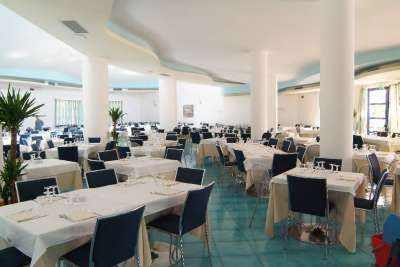 Sala ristorante ampia con tavoli apparecchiati e sedie blu.