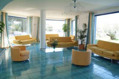 Sala luminosa con divani gialli e ampie finestre.