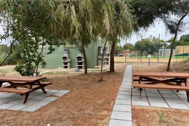 Area picnic con tavoli di legno e barbecue.