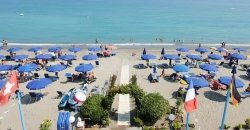 Spiaggia affollata con ombrelloni blu.