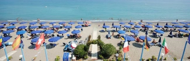 Ombrelloni blu su spiaggia vista dall'alto.