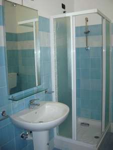 Bagno con piastrelle azzurre, lavabo e cabina doccia.