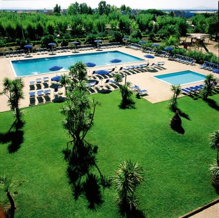 Due grandi piscine con lettini e ombrelloni su un prato verde.