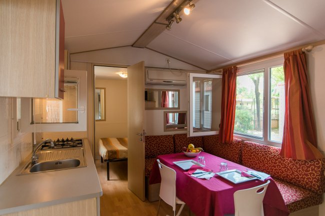 Interno di una casa mobile con cucina e tavolo apparecchiato.