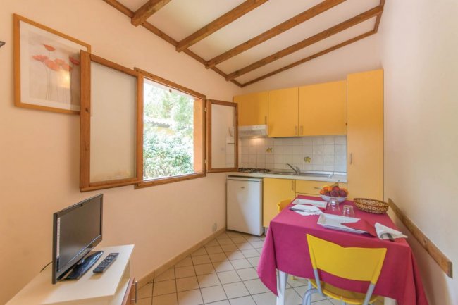 Cucina gialla con tavolo apparecchiato, finestra aperta e TV.