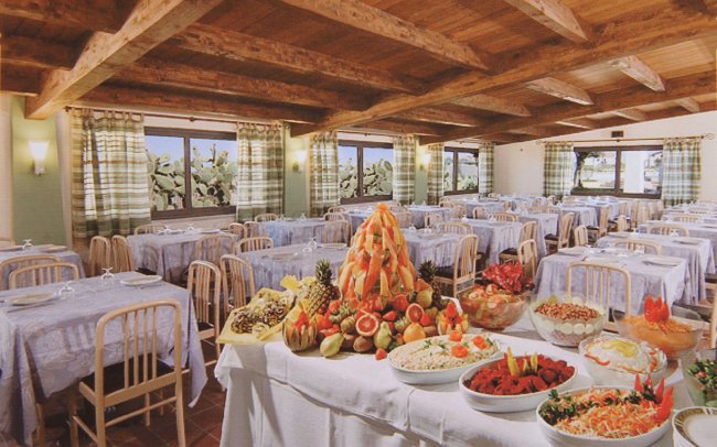 Sala da pranzo con buffet ricco e tavoli apparecchiati.