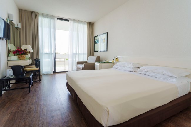 Stanza d'hotel con letto matrimoniale e poltrona vicino a una finestra.