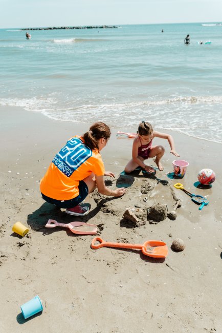 Due persone costruiscono un castello di sabbia sulla spiaggia.