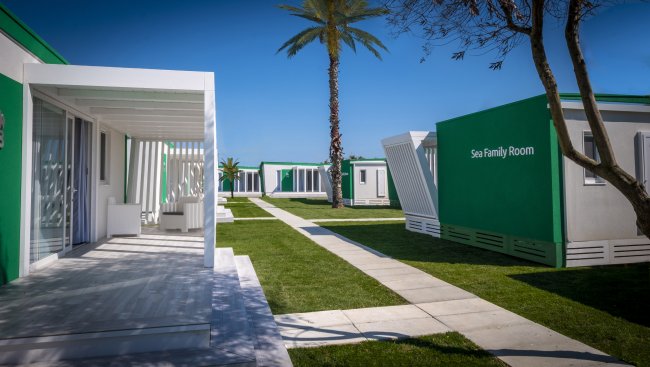Complesso di moderni bungalow bianchi e verdi con sentieri e palme.