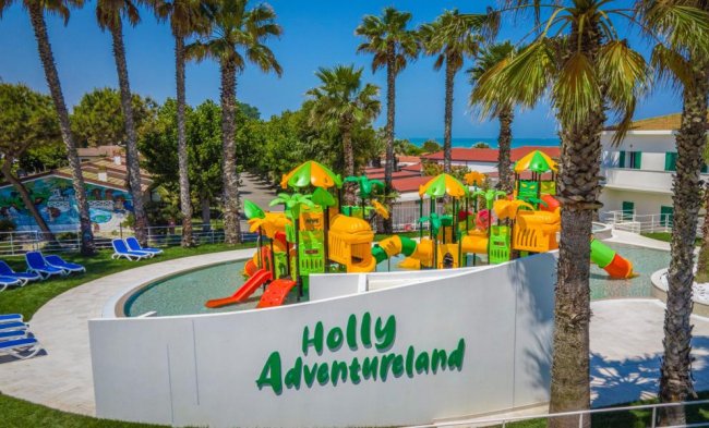 Parco giochi acquatico con scivoli colorati e palme.