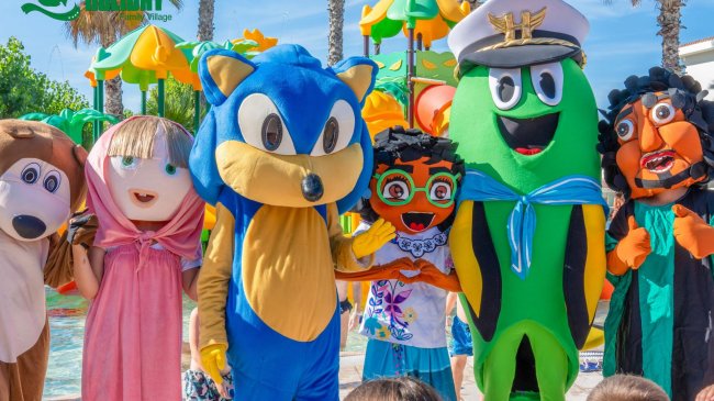 Mascotte colorate posano insieme davanti a giochi d'acqua in un parco acquatico.
