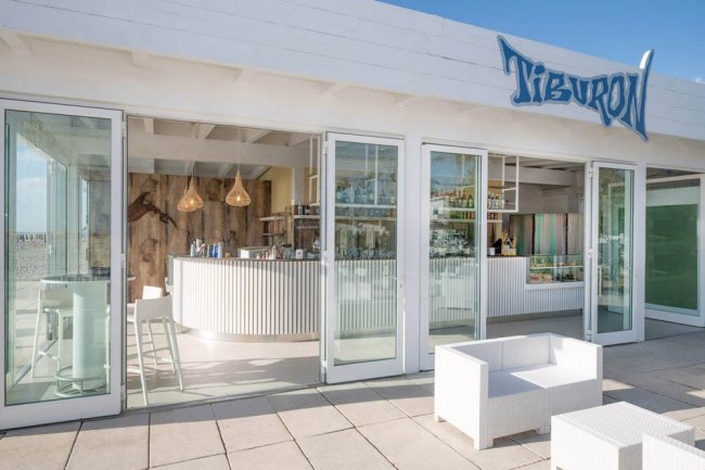 Bar moderno con pareti di vetro, all'esterno mobili bianchi.