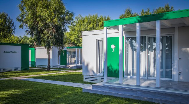 Complesso di suite moderne con facciate bianche e verdi, immerse nel verde.