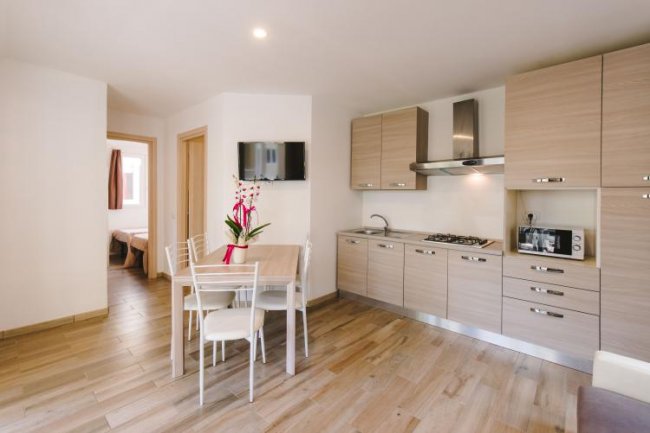 Cucina moderna con tavolo da pranzo e TV a parete.
