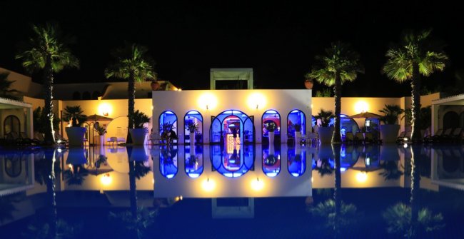 Edificio illuminato con piscina riflettente di notte.