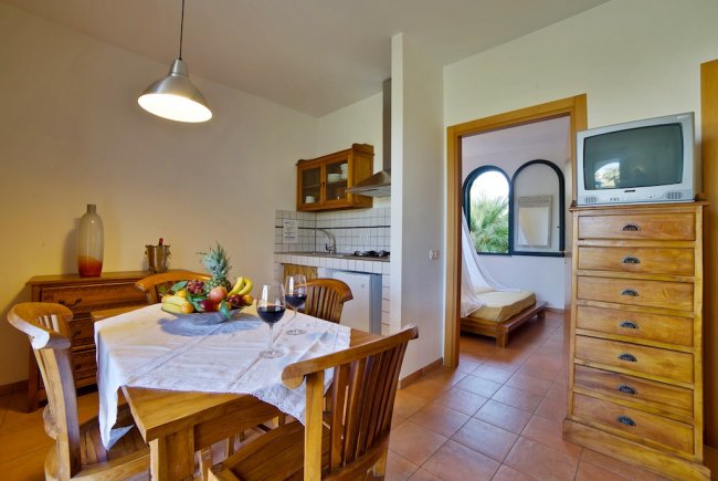 Sala da pranzo con tavolo apparecchiato e cucina aperta.