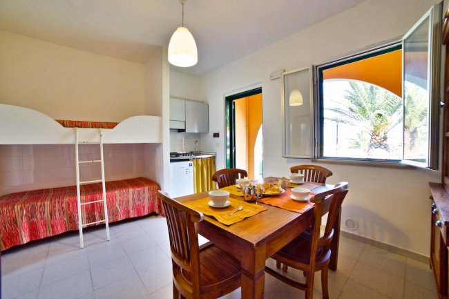 Cucina con tavolo quadrato e letti a castello.