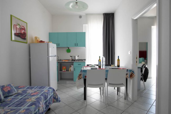 Cucina con tavolo apparecchiato e frigorifero, stile moderno.